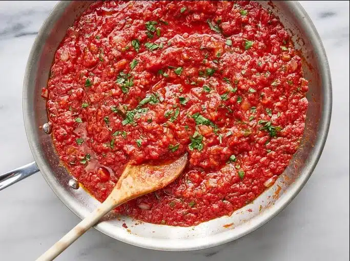 A bowl of marinara pasta garnished with fresh basil and Parmesan, showcasing the perfect blend of flavors and textures.