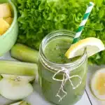 A glass filled with a refreshing cucumber smoothie surrounded by fresh cucumber slices