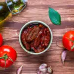 A bowl of authentic marinara sauce beside a tube of tomato paste, highlighting the differences in ingredients and texture.