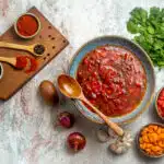 A bowl of pasta topped with the perfect liquid marinara sauce, garnished with basil leaves.