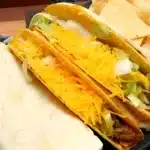 A delicious and cheesy gordita crunch served with a side of salsa and fresh greens