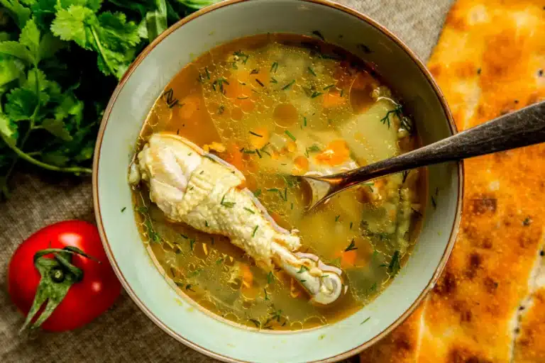 A bowl of rich and flavorful broth enhanced with chicken bouillon, surrounded by fresh ingredients