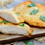 Golden crispy chicken cutlets served on a white plate with lemon wedges