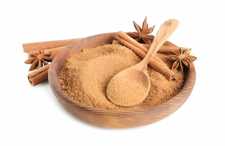 A bowl of cinnamon sticks next to a pile of granulated sugar