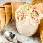 A bowl of edible sugar cookie dough garnished with colorful sprinkles, ready to be enjoyed