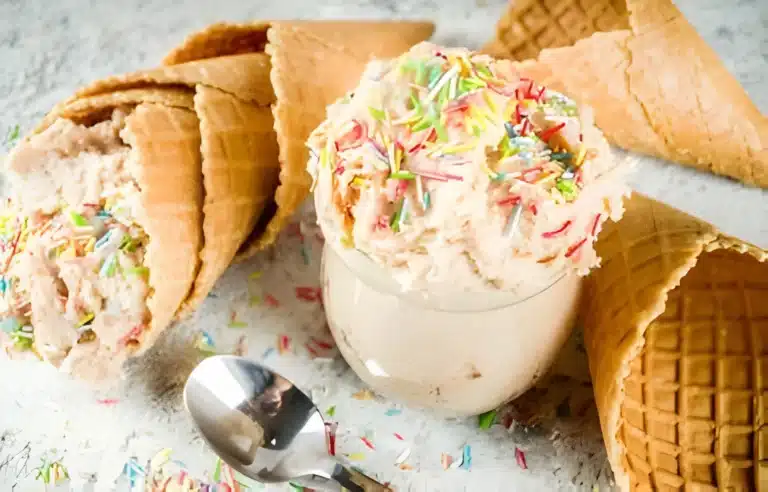 A bowl of edible sugar cookie dough garnished with colorful sprinkles, ready to be enjoyed