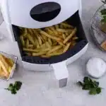 Frozen fries being air fried in a basket