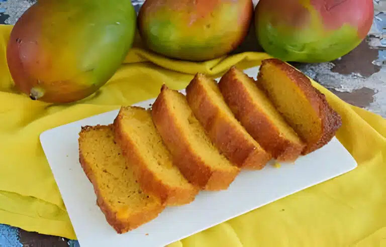 Freshly baked mango bread on a cooling rack, with vibrant mango pieces visible, ready to be enjoyed.