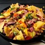 Sizzling steak nachos with melted cheese, fresh guacamole, and a sprinkle of cilantro on top