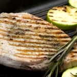 Succulent grilled swordfish steak served with lemon wedges 🍋🐟